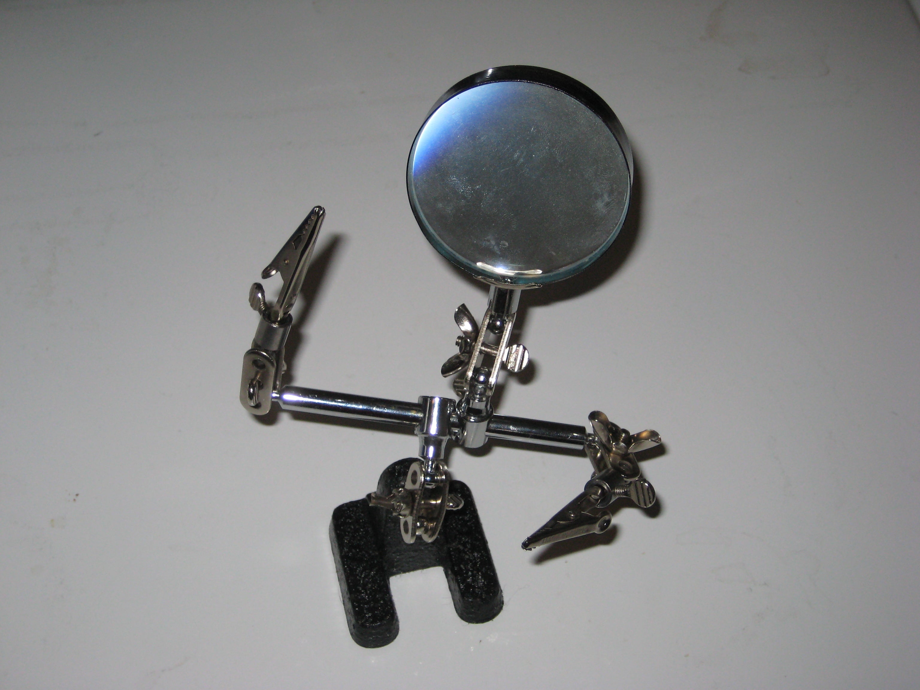 Helping hands station with multiple articulating arms holding components for electronics work