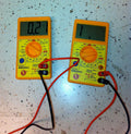 Digital multimeter showing voltage and amp readings