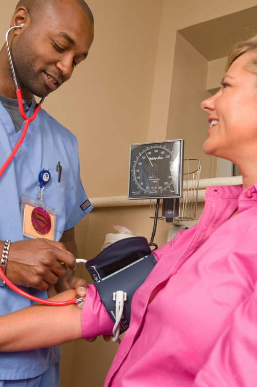 Nurse measuring patient blood pressure with manual BP cuff and stethoscope