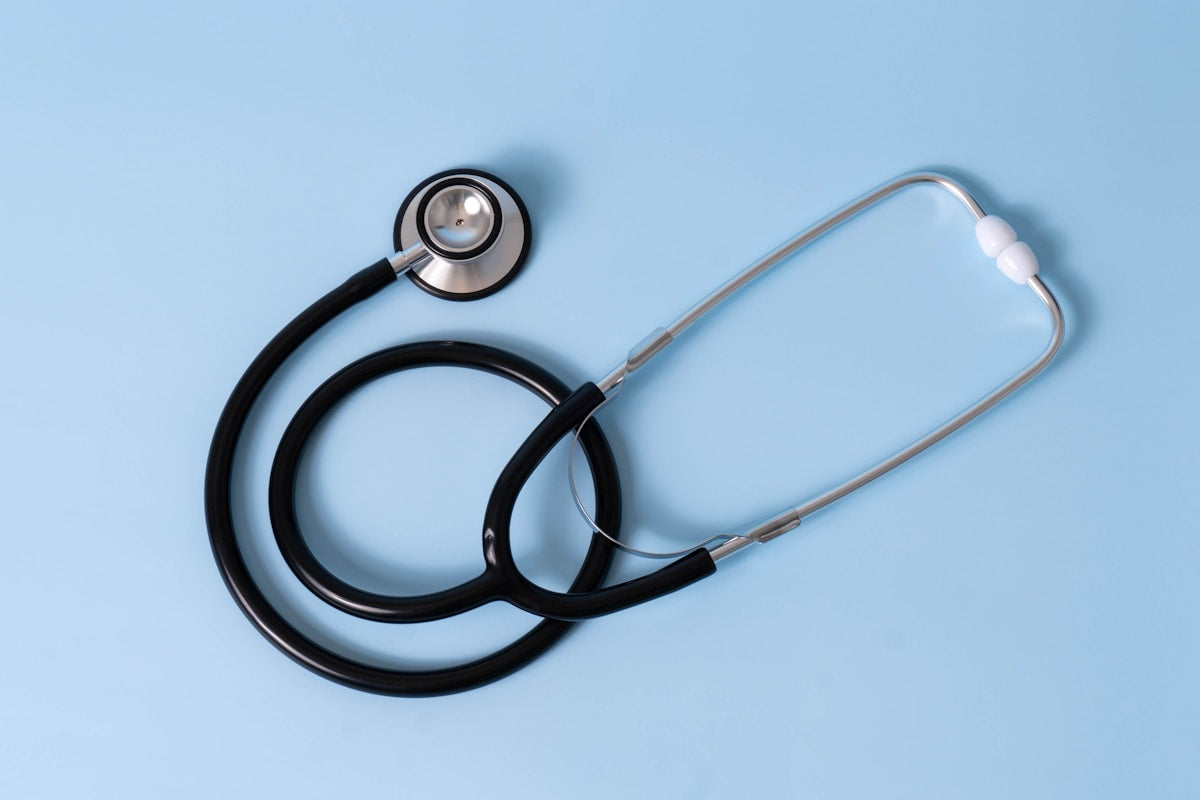 Black clinical stethoscope on blue background